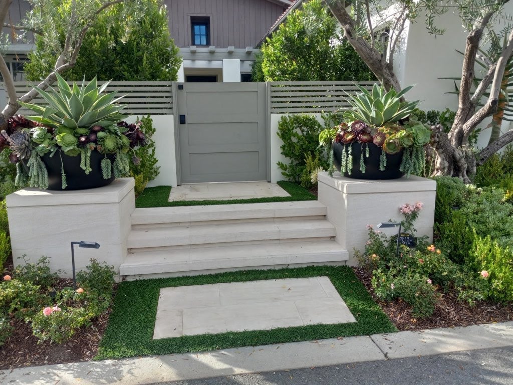 Elegant modern front yard landscaping with concrete steps, lush greenery, and decorative succulents, showcasing high-quality residential construction by Producers Construction.
