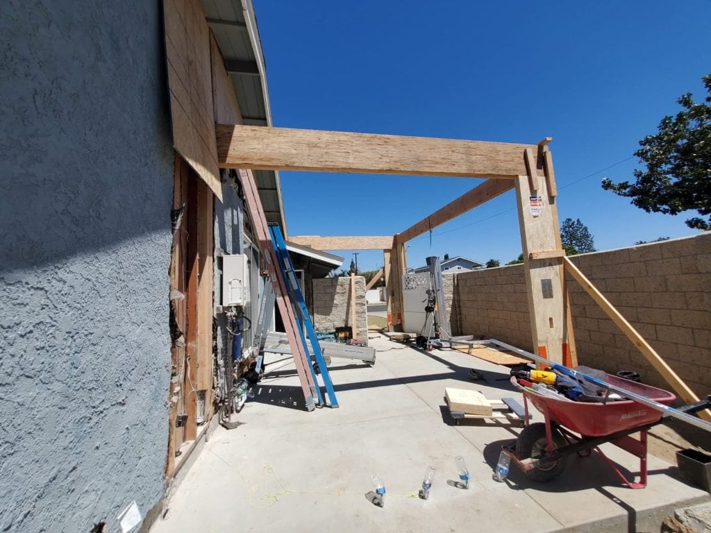 Excavation and framing of a residential outdoor patio or structure with wooden beams at a construction site.